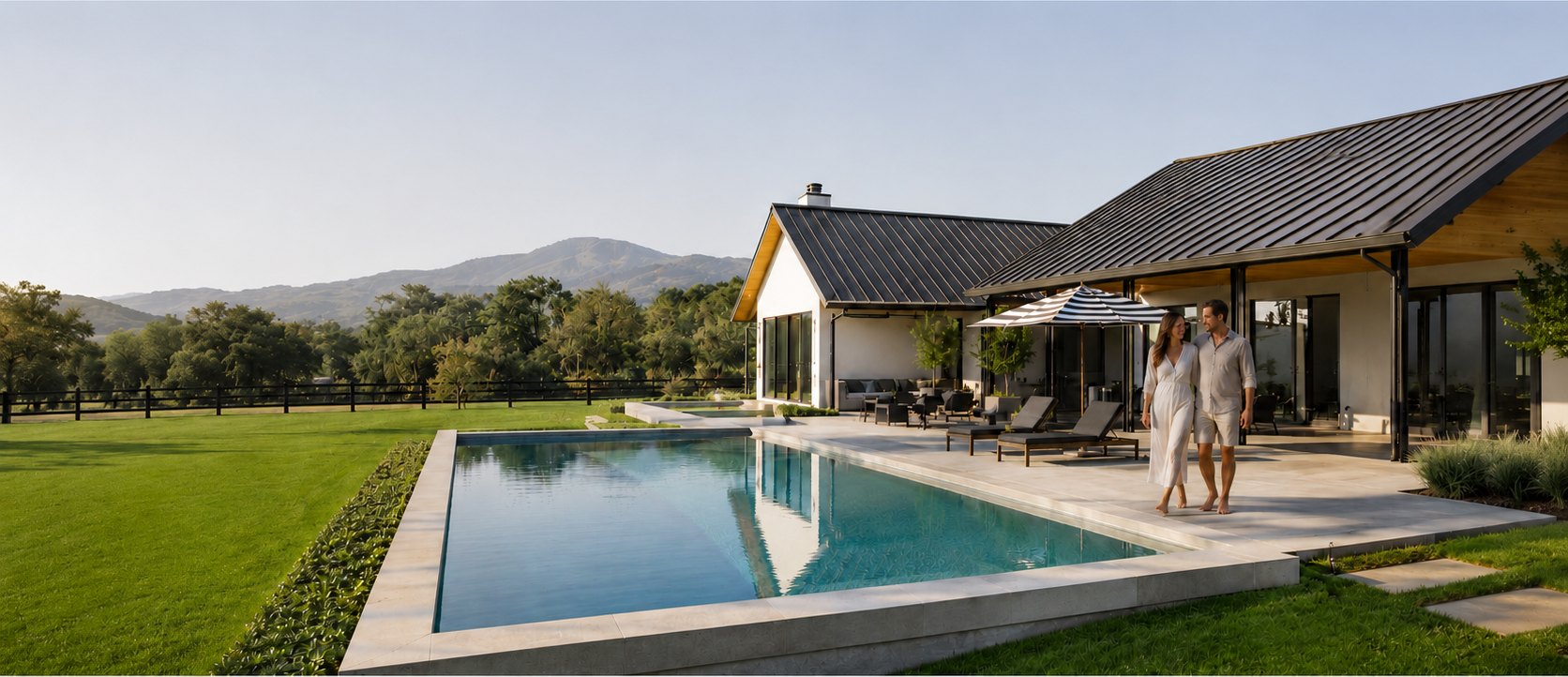 A couple walking beside the pool with the mountains in the distance
